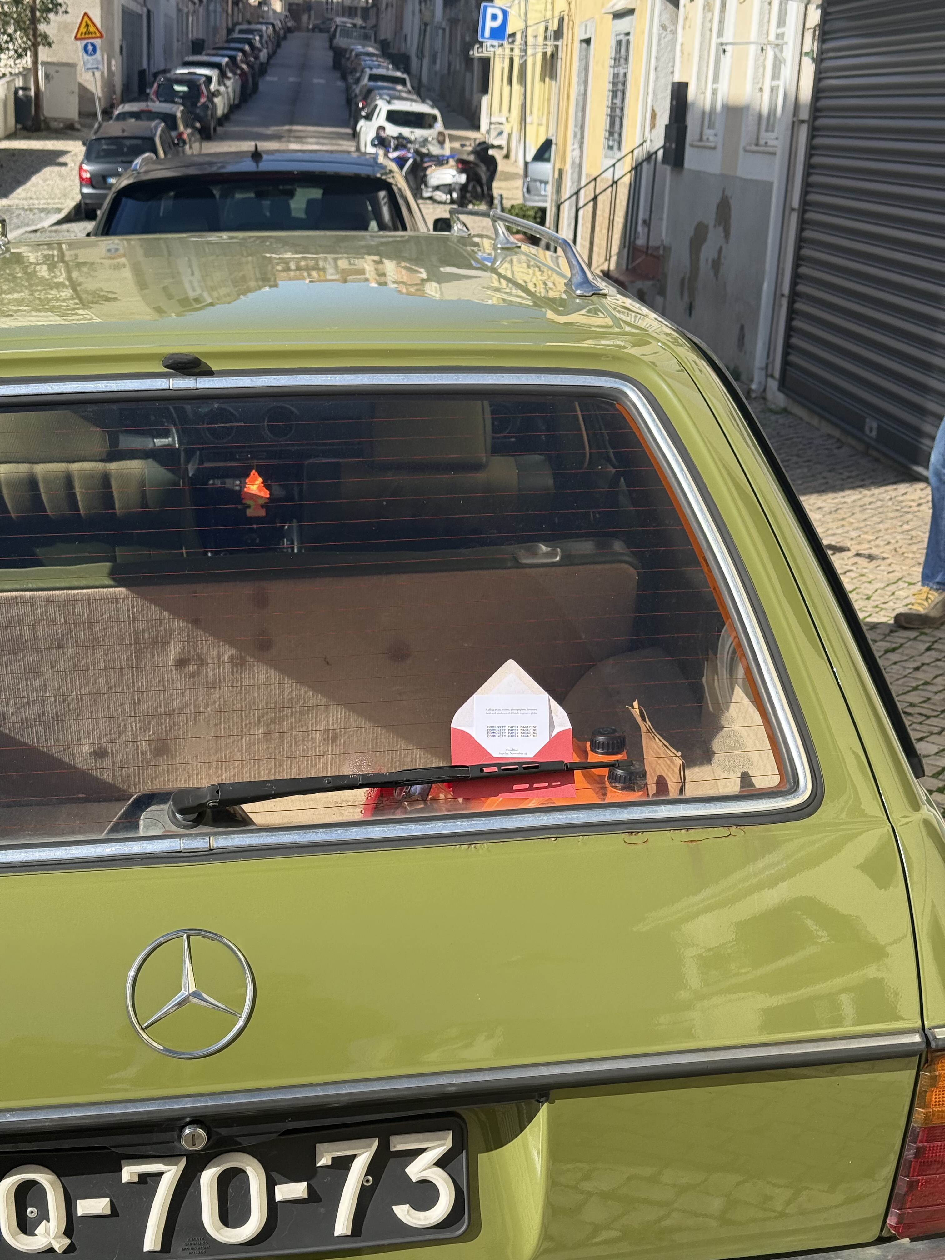 A tiny red 2Pages envelope spotted in the back window of a green car in Lisbon
